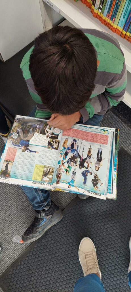 Ein Kind sitzt und schmökert in Büchern. 