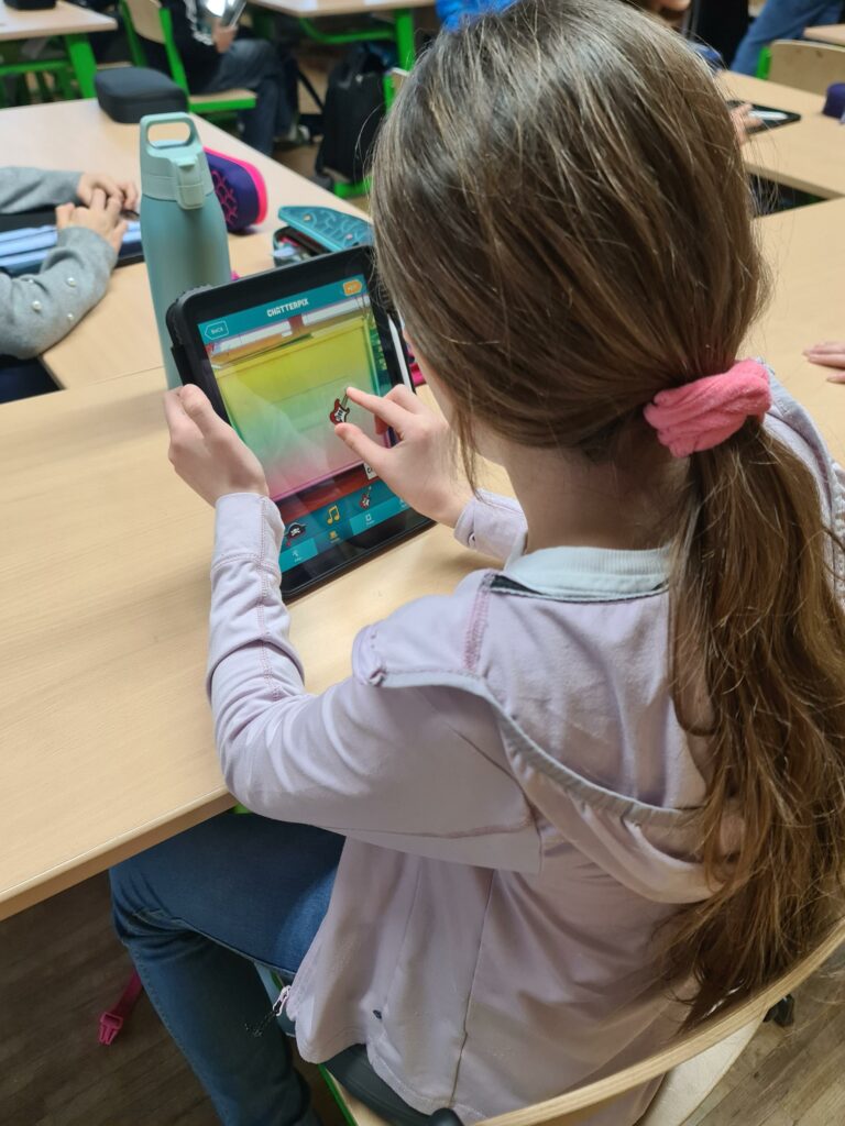 Digitale Bildung. Ein Kind sitzt mit einem Tablet und bearbeitet ein Musikinstrument. 