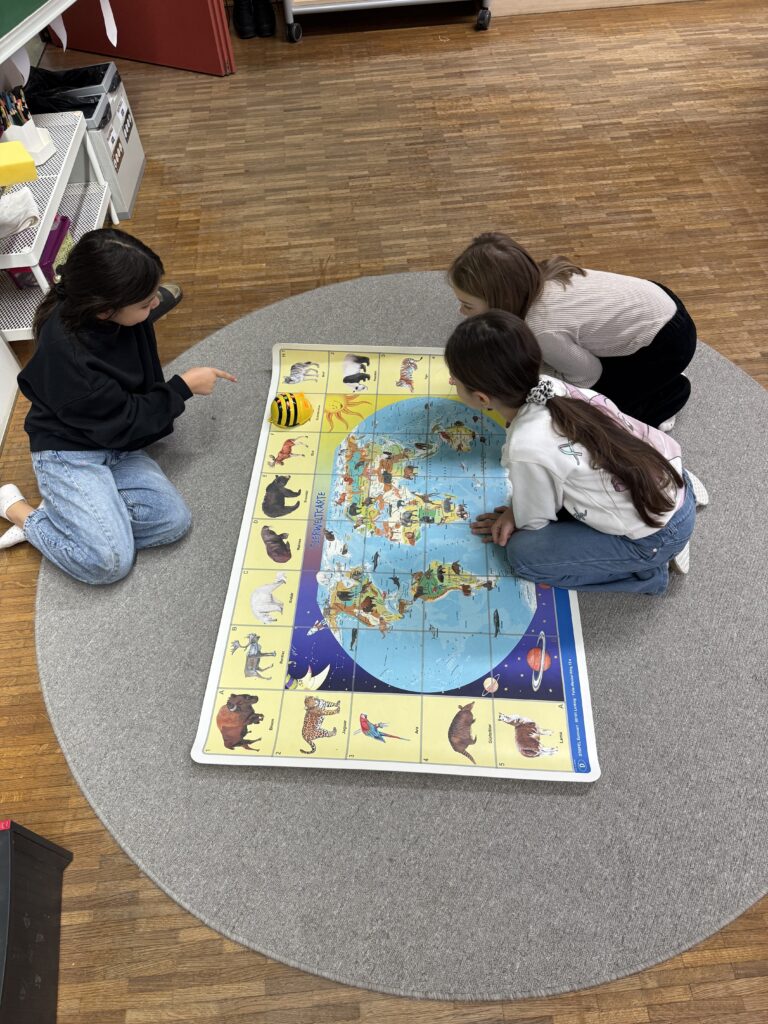 E-Education: Kinder arbeiten mit den Bei-Bot auf einer Weltkarte.