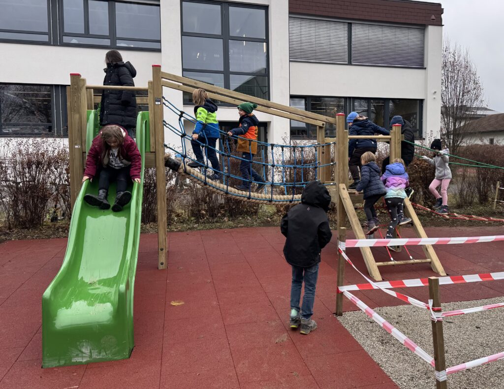Pause im Wiesenhof. Kinder spielen und rutschen auf den neuen Spielgeräten.