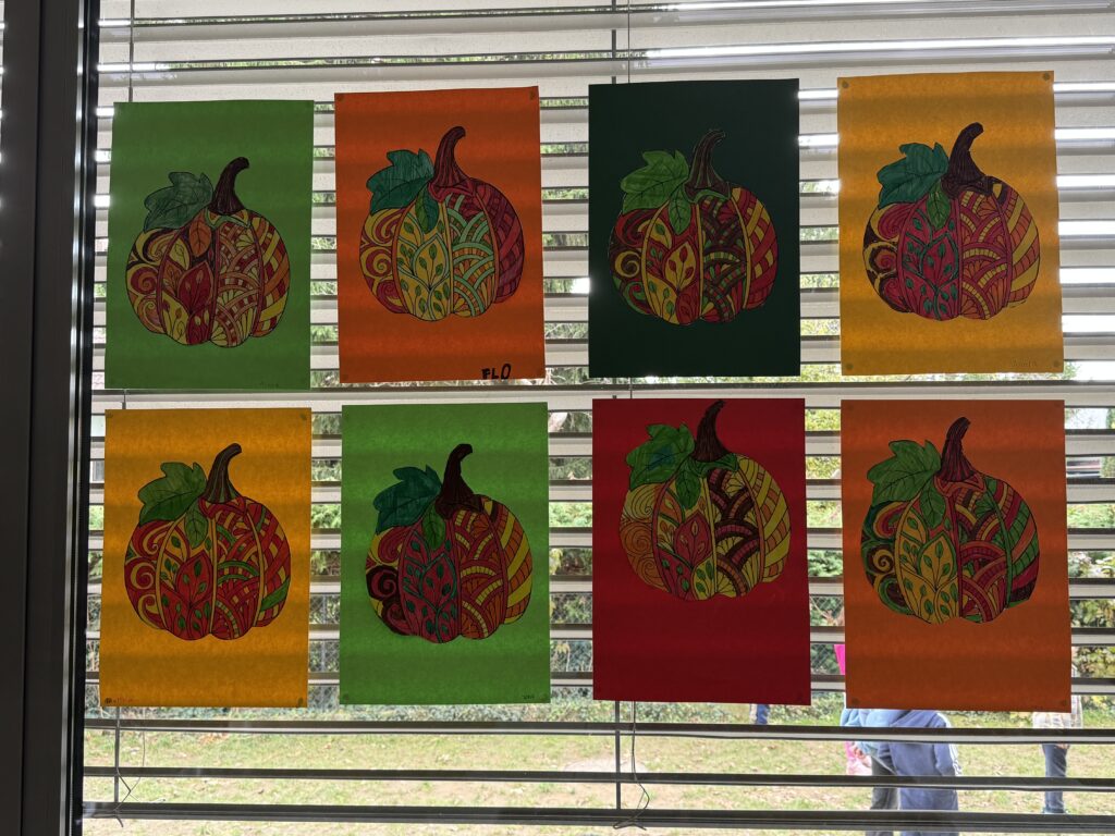 Auf dem Fenster hängen schön und bunt gestaltete Kürbis der Kinder. 