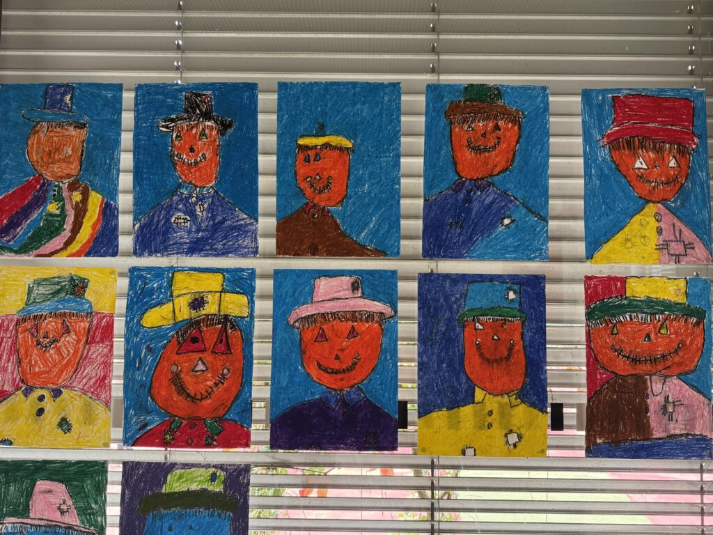 Hier hängen bunte Vogelscheuchen der Kinder am Fenster. 