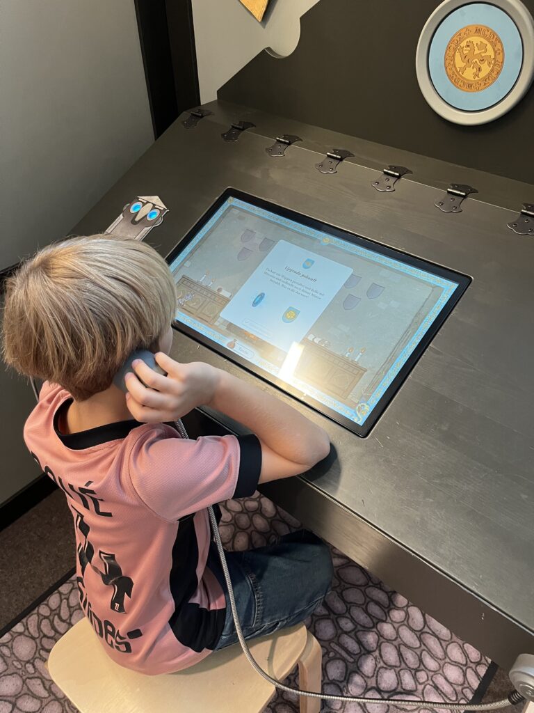 Ausstellung im Frida und Fred zum Thema: "Damals 1410". Ein Kind sitzt vor einem Tablet.