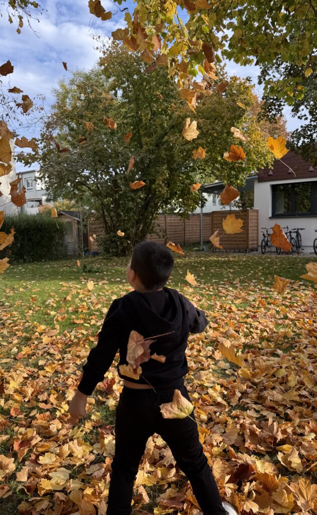 Kinder sammeln bunte Herbstblätter im Garten. 