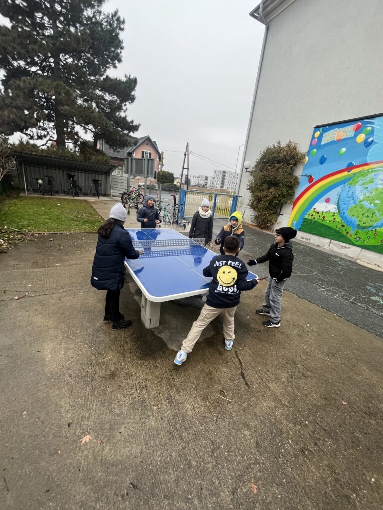 Aktiv in der Hofpause. Kinder spielen Tischtennis. 