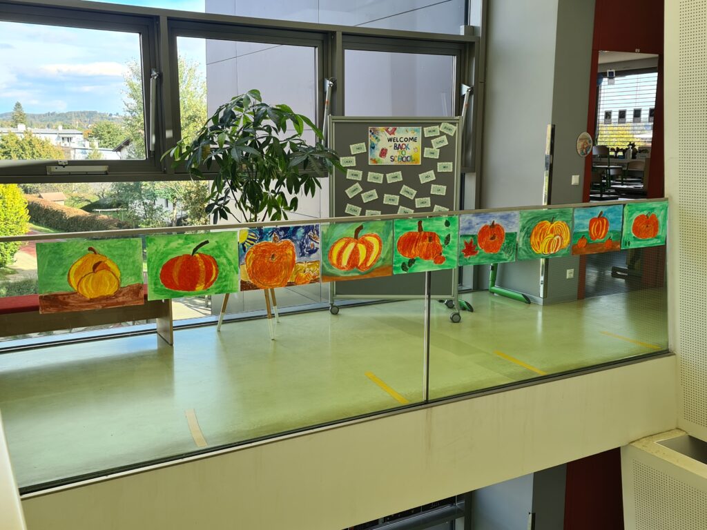 Im Gang vor der Klasse hängen selbst gemalte Kürbisbilder. 