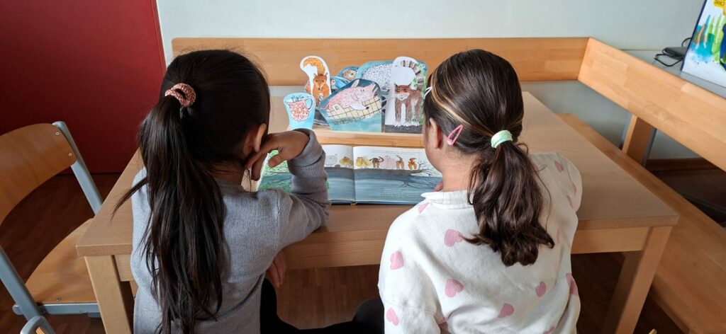 Zwei Kinder lesen das Buch " Komm, sagt die Katze" und stellen dabei die vorbereiteten Figuren auf. 