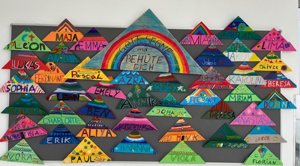 Auf einer Tafel hängen viele bunt bemalte Segenshüte der Schulanfänger. 