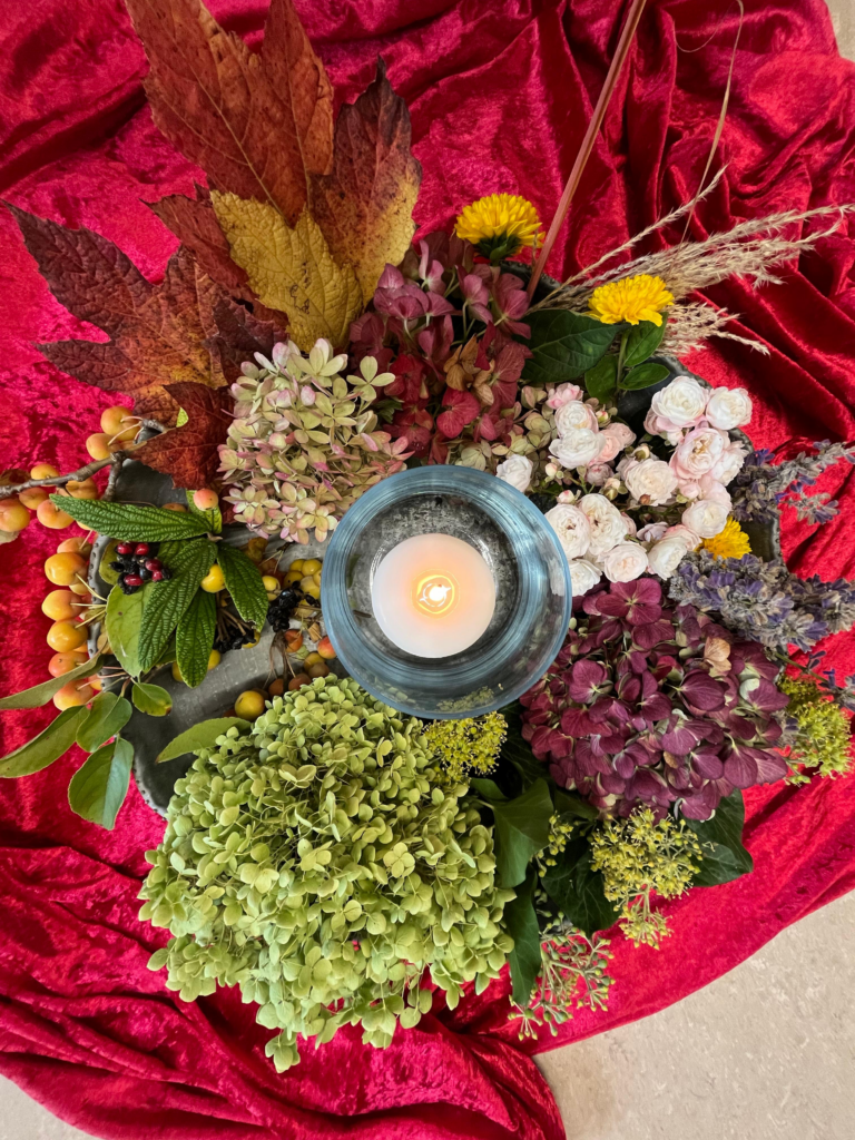 Wunderschöner Blumenkranz mit einer brennenden Kerze.